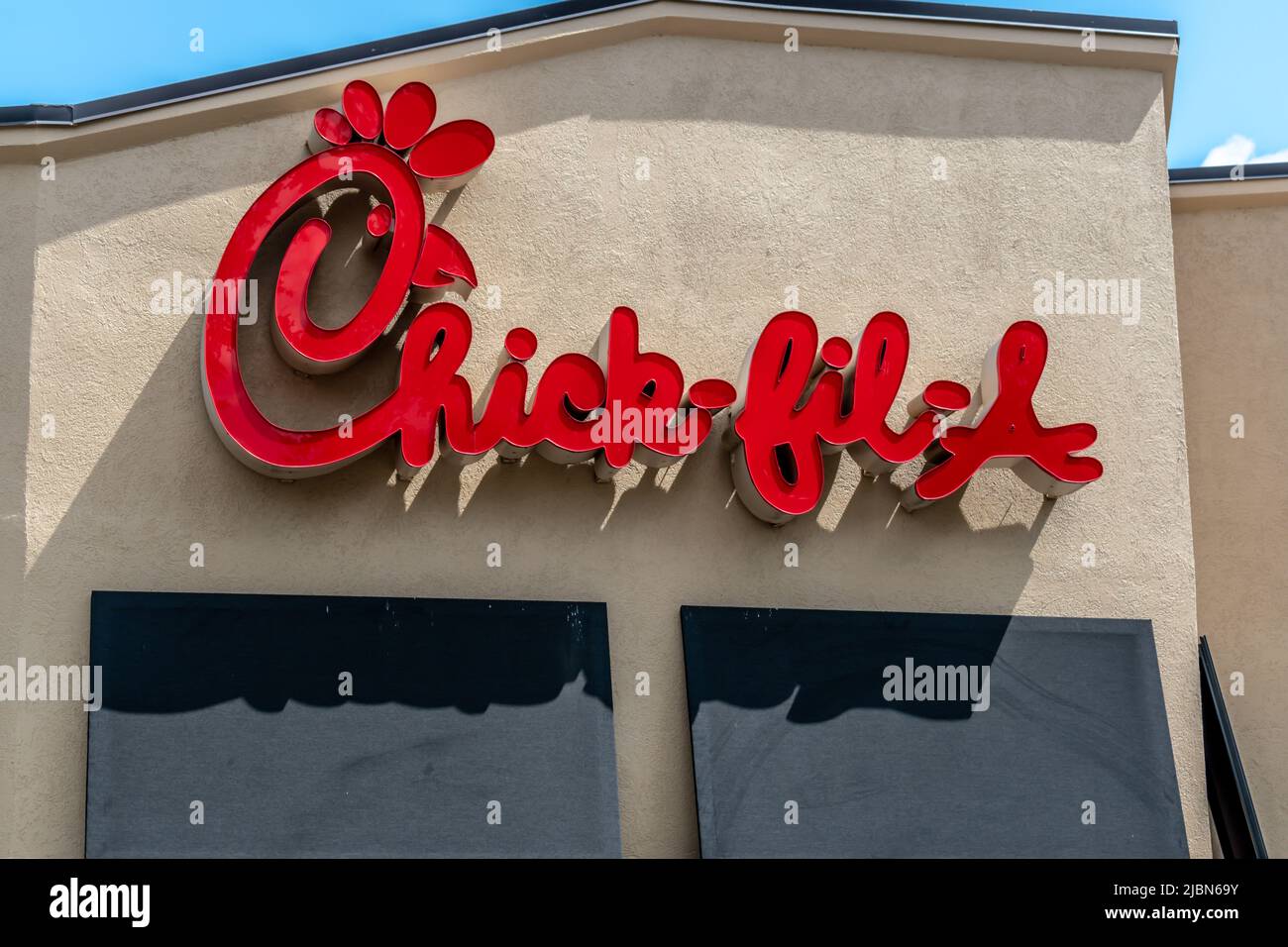 Chick-fil-Eine Außenfassade-Marke und Logo-Beschilderung in roten Schriftzügen über schwarzen Markisen an einem sonnigen Tag mit blauem Himmel und Wolken in Charlotte. Stockfoto