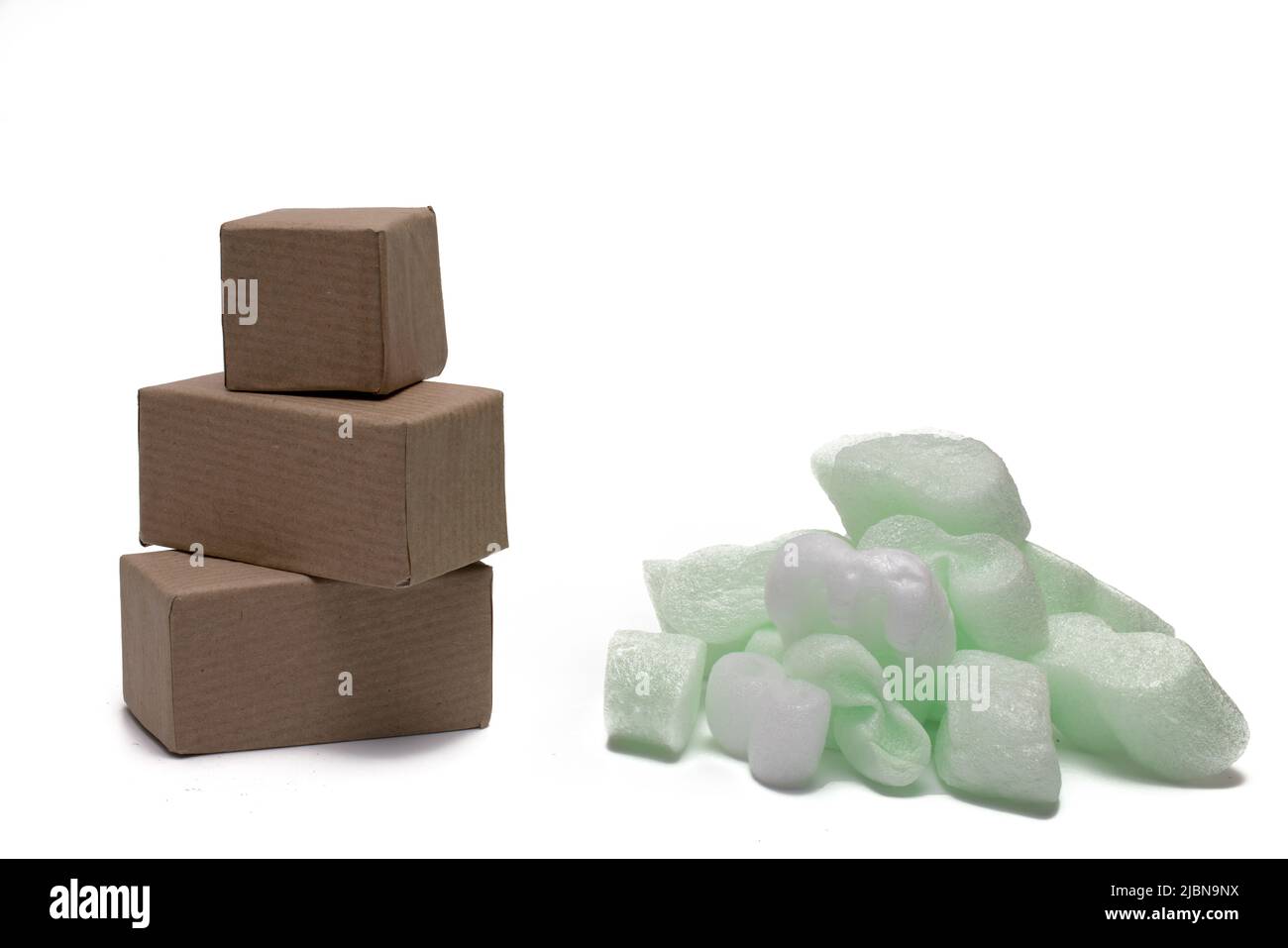 Nahaufnahme eines Stapels kleiner Kartonverschiffungskartons neben einem Stapel großer, weich grün weißer Verpackungssplitter, um empfindliche Waren während des Sh zu schützen Stockfoto