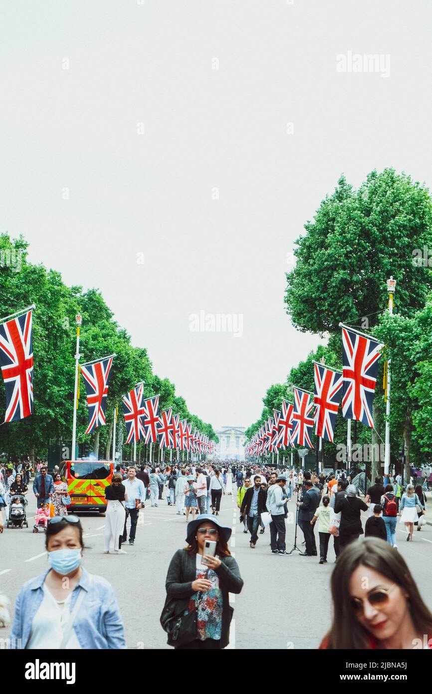 Touristen laufen auf der Mall in London, umgeben von Union Jack Flaggen. Stockfoto