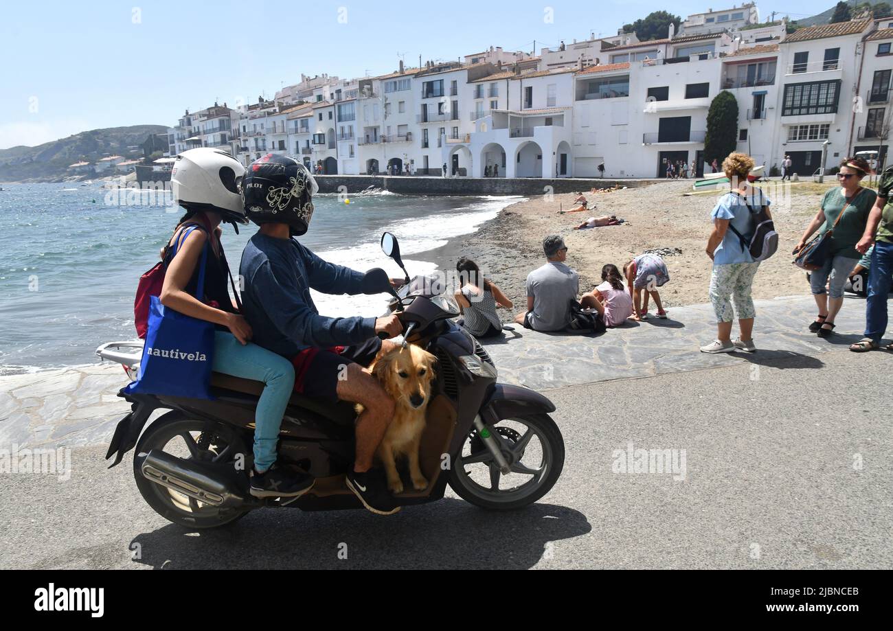 Ein Paar mit einem Scooter und einem Hund an Bord in Cadaques, einer spanischen Stadt in der Comarca Alt Empordà, in der Provinz Girona, Katalonien, Spanien. Stockfoto
