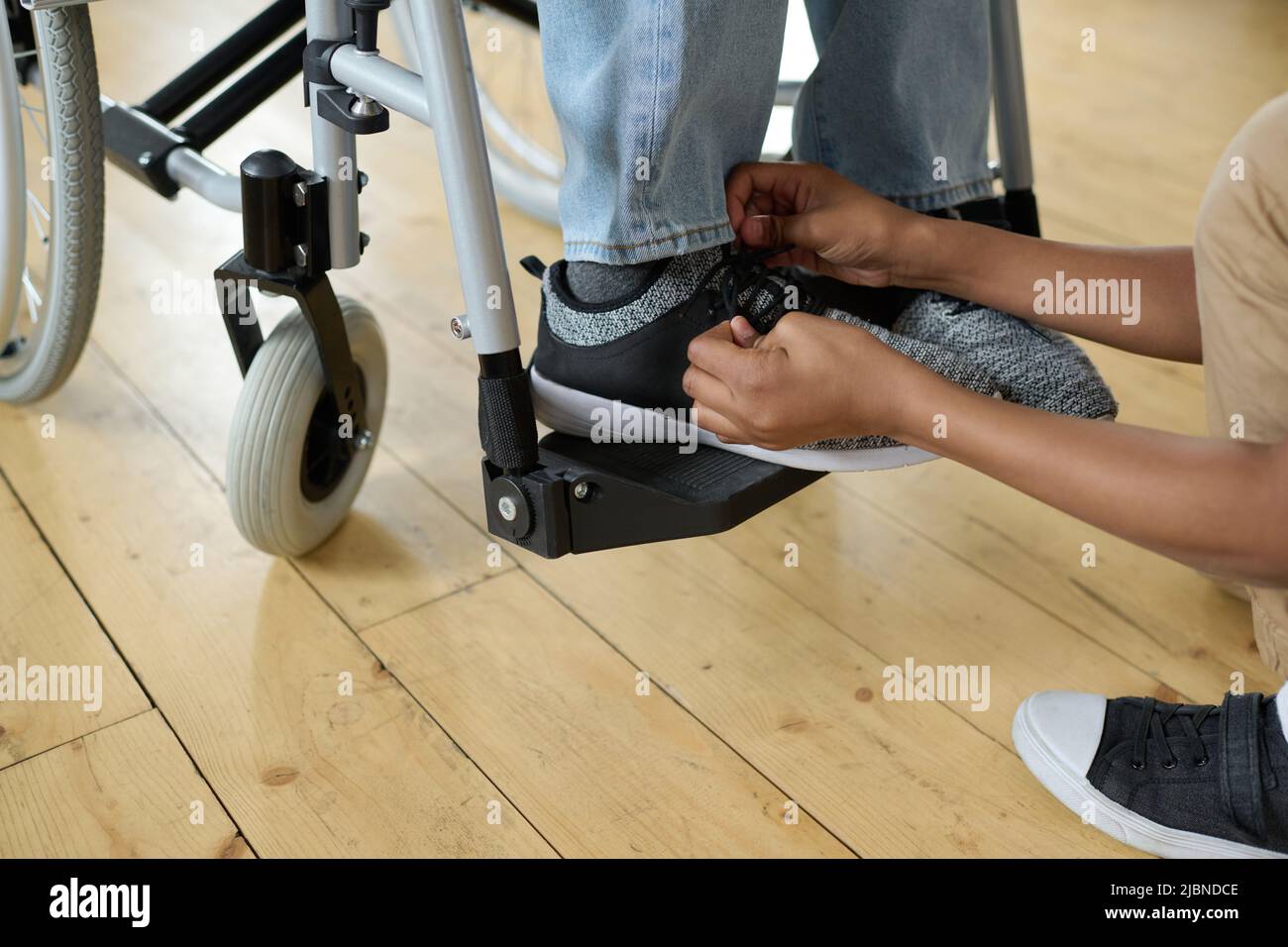 Nahaufnahme eines kleinen Jungen, der Schuhbänder auf die Schuhe seines behinderten Vaters kitzelt, während er im Rollstuhl sitzt Stockfoto