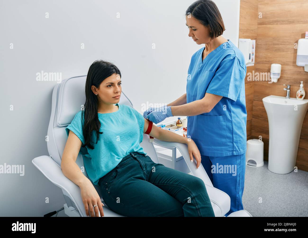 Krankenschwester, die Blut für Allergenuntersuchungen durch Blutentnahme in Reagenzgläsern im Labor nimmt Stockfoto