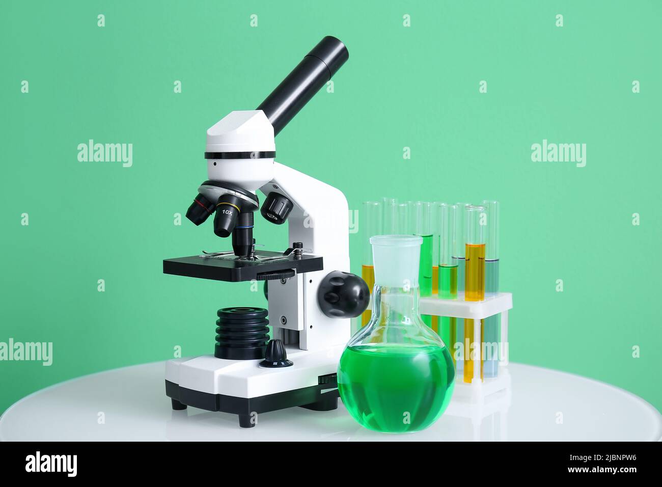 Moderne Mikroskop- und Laborgläser auf Tisch in der Nähe der grünen Wand Stockfoto