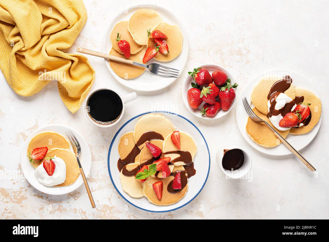 Pfannkuchen mit Schlagsahne, Erdbeeren und Schokoladensauce. Draufsicht. Süße Pfannkuchen zum Familienfrühstück Stockfoto