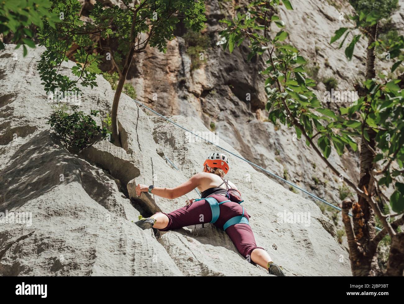 Athletische Frau in Schutzhelm und Schuhen Klettern auf Felswand mit Top-Seil und Klettergurt in Paklenica Nationalpark-Website in Croat Stockfoto