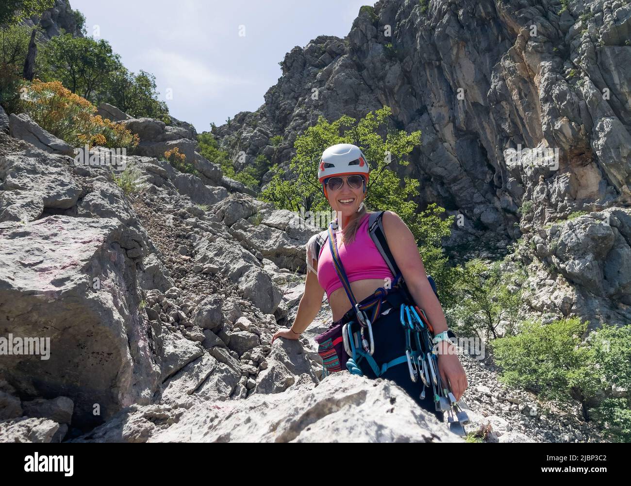 Fröhliche lächelnde Alpinistin Frau im schützenden Helm Klettergurt mit Schnellzuchten in Paklenica Nationalpark Schlucht in Kroatien. Aktive extreme spo Stockfoto