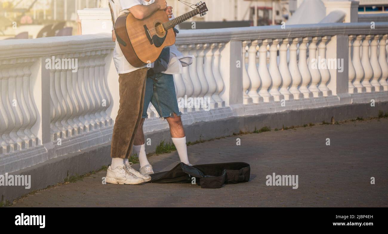 Straßenmusiker mit Gitarre und einem Almosenbeutel für Geldspenden. Stockfoto