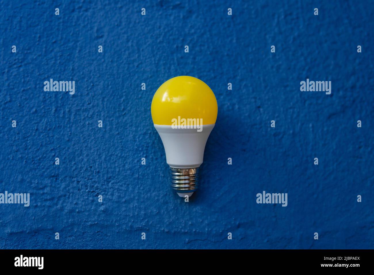 Gelbe Glühbirne über einer blauen Wand im Freien Stockfoto