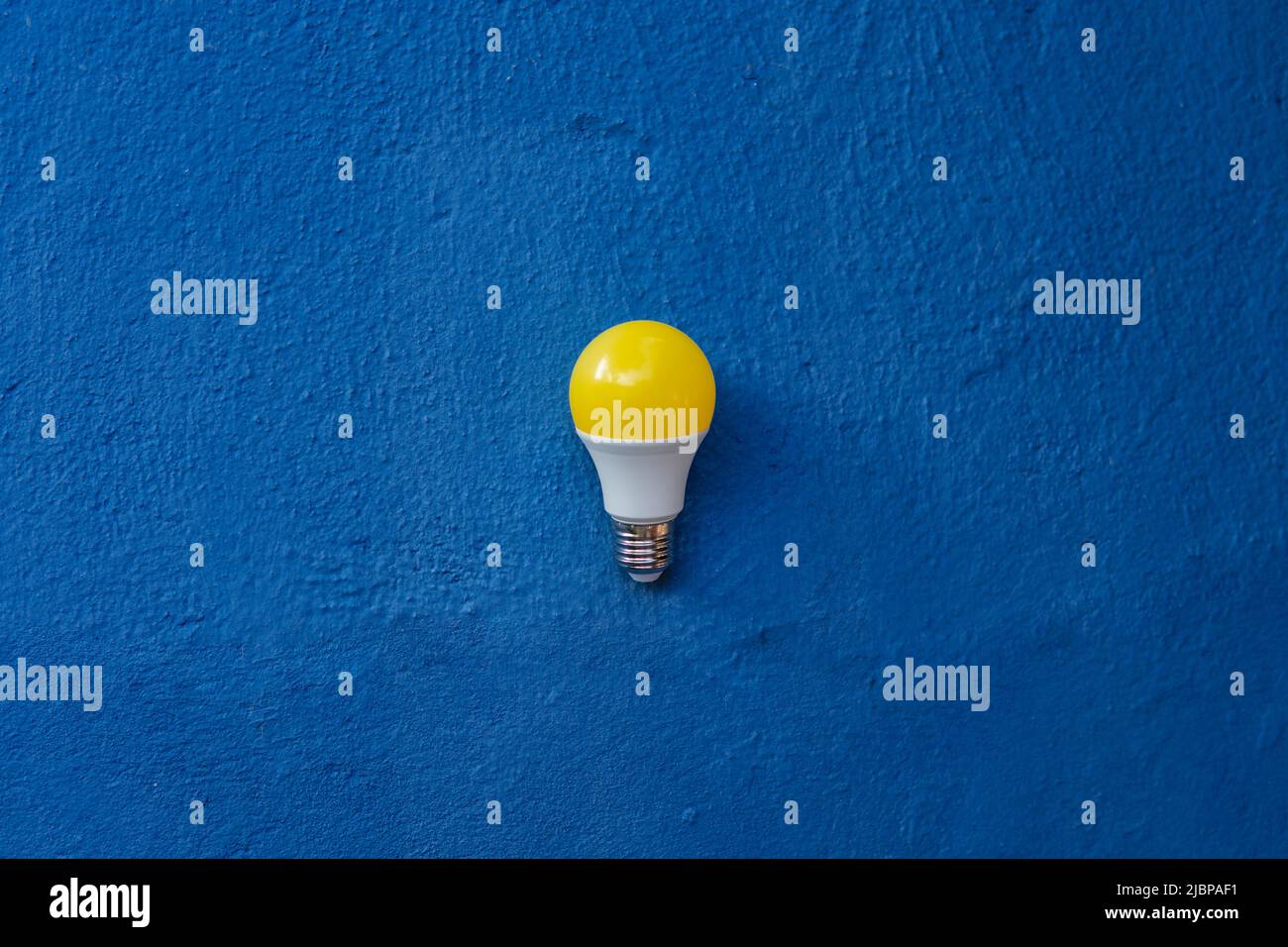 Gelbe Glühbirne über einer blauen Wand im Freien Stockfoto