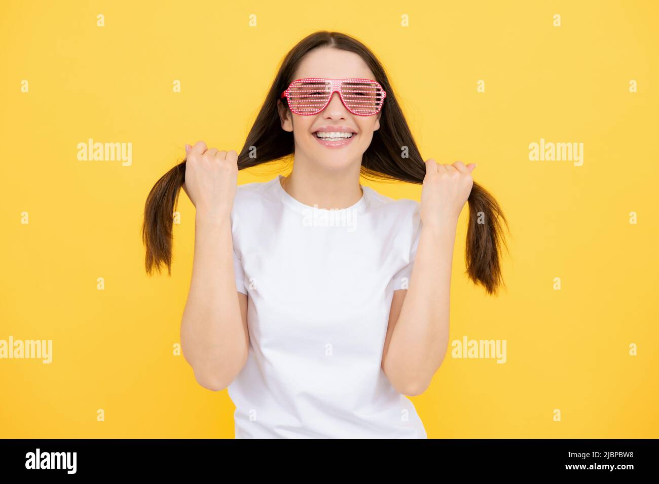Schönheit lustige Teenager-Mädchen mit Party-Brille, gelber Hintergrund. Überrascht junge Frau mit Spaß Brille. Stockfoto