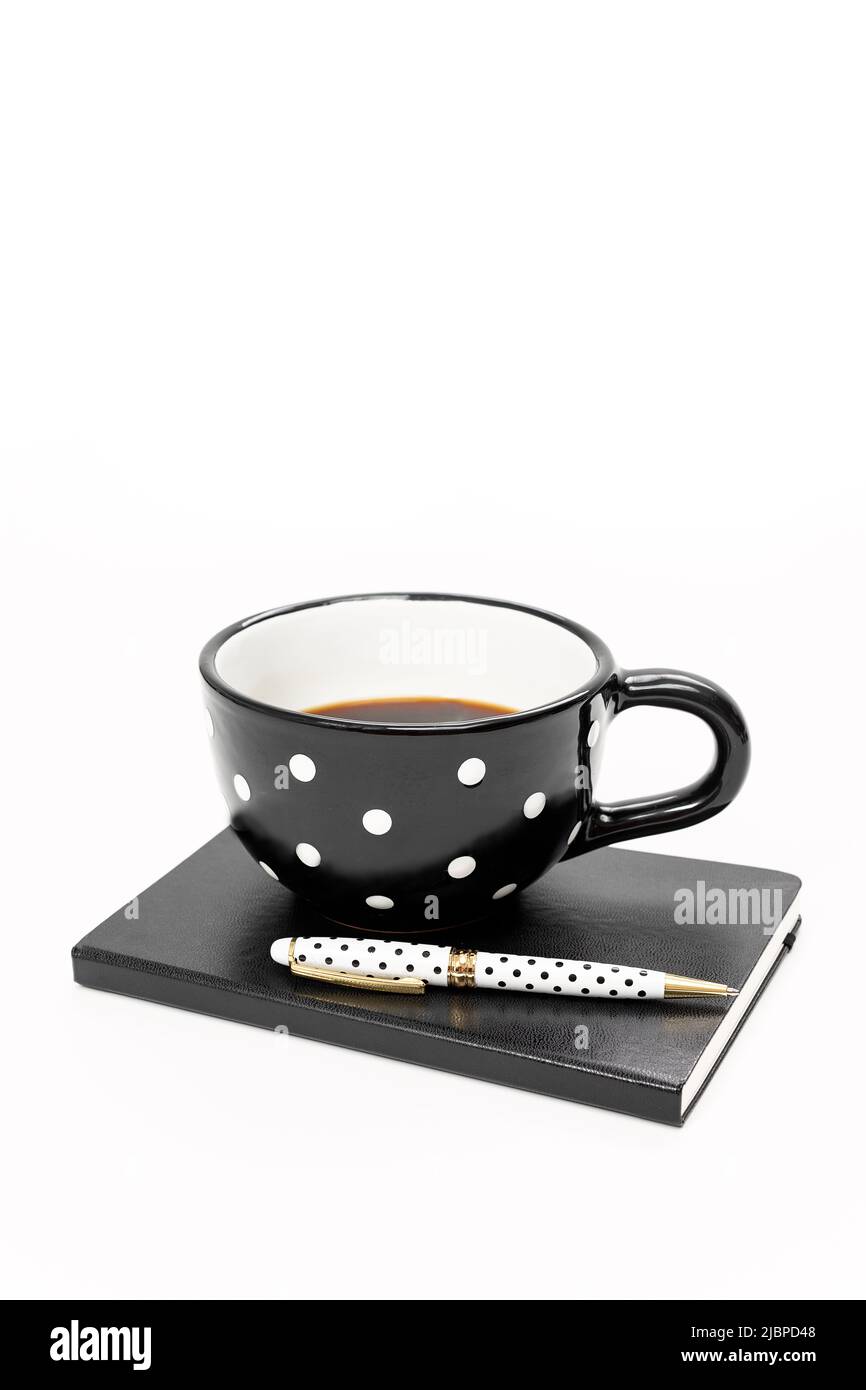 Schreibtisch mit schwarzem und weißem Design, Becher mit Punktmuster und Notizbuch Stockfoto