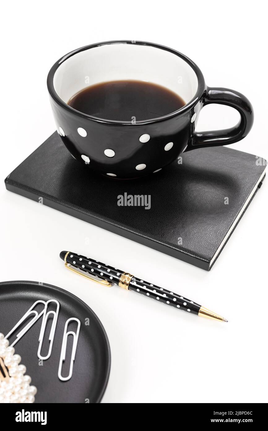 Schreibtisch mit schwarzem und weißem Design, Becher mit Punktmuster und Notizbuch Stockfoto