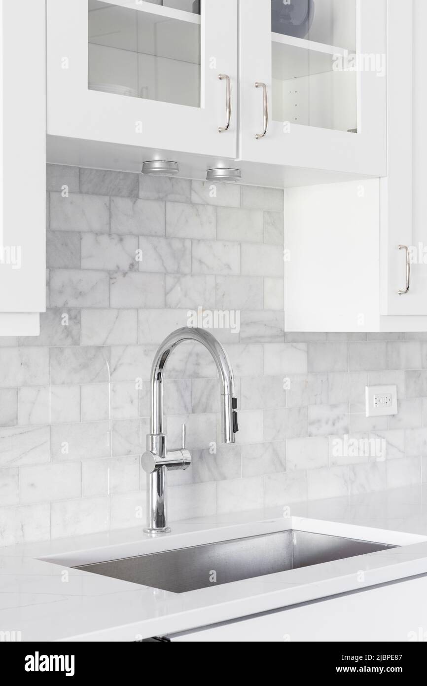 Ein Küchenwaschbecken Detail mit weißen Schränken und einer marmornen U-Bahn-Fliese backsplash aufgenommen. Stockfoto