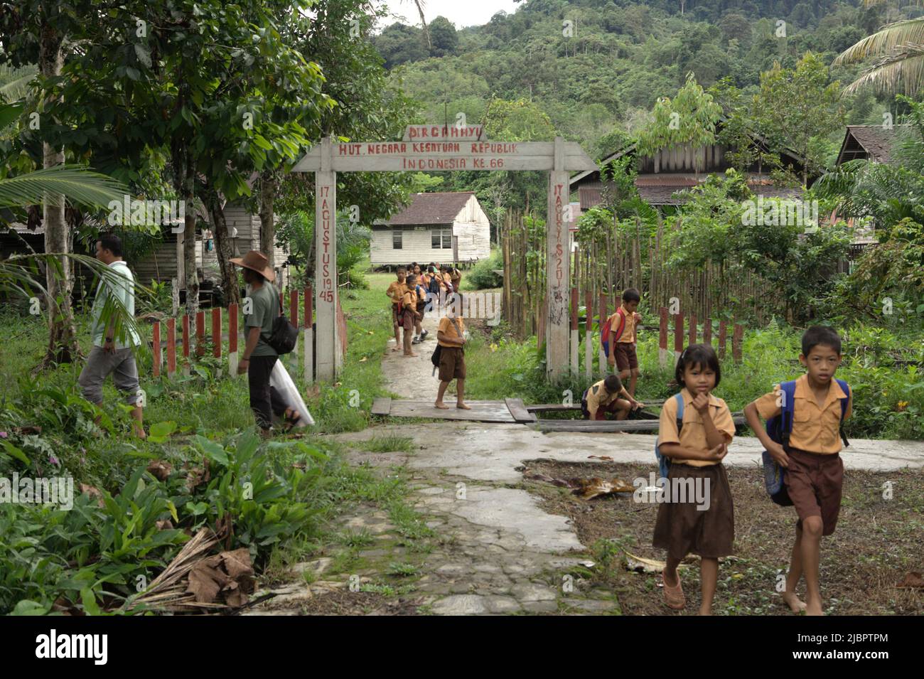 Schulkinder, die nach dem Besuch einer Grundschule im abgelegenen Dorf Nanga Raun in Kalis, Kapuas Hulu, West Kalimantan, Indonesien, auf einem ländlichen Pfad spazieren gehen. Stockfoto