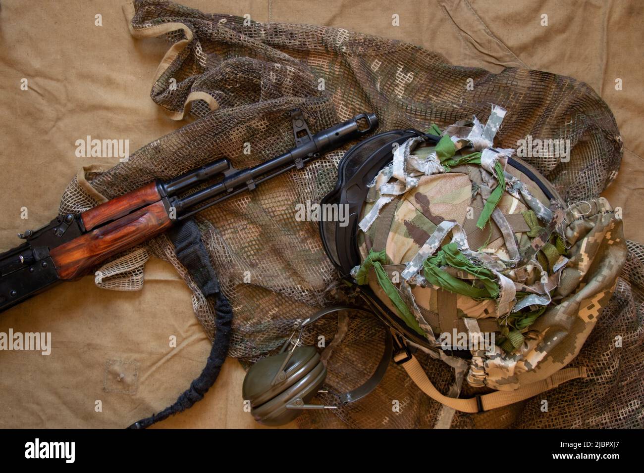 Kampfmaschine und gepanzerter Helm Tarnung auf grünem Hintergrund, militärische Waffen des ukrainischen Soldaten, militärische Ausrüstung, gepanzerter Helm auf t Stockfoto