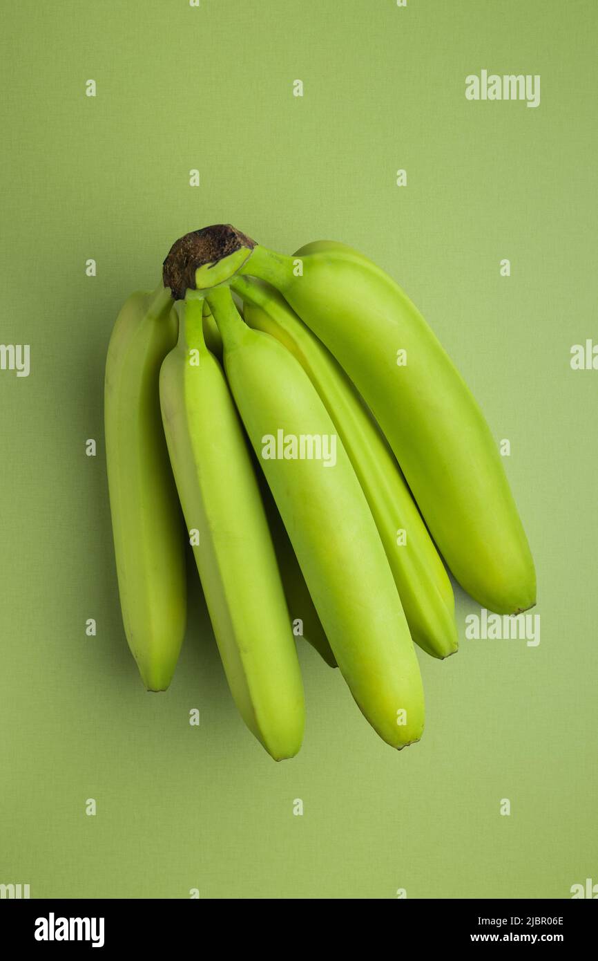 Unreife grüne Bananen auf einem grünen Tisch. Draufsicht. Stockfoto