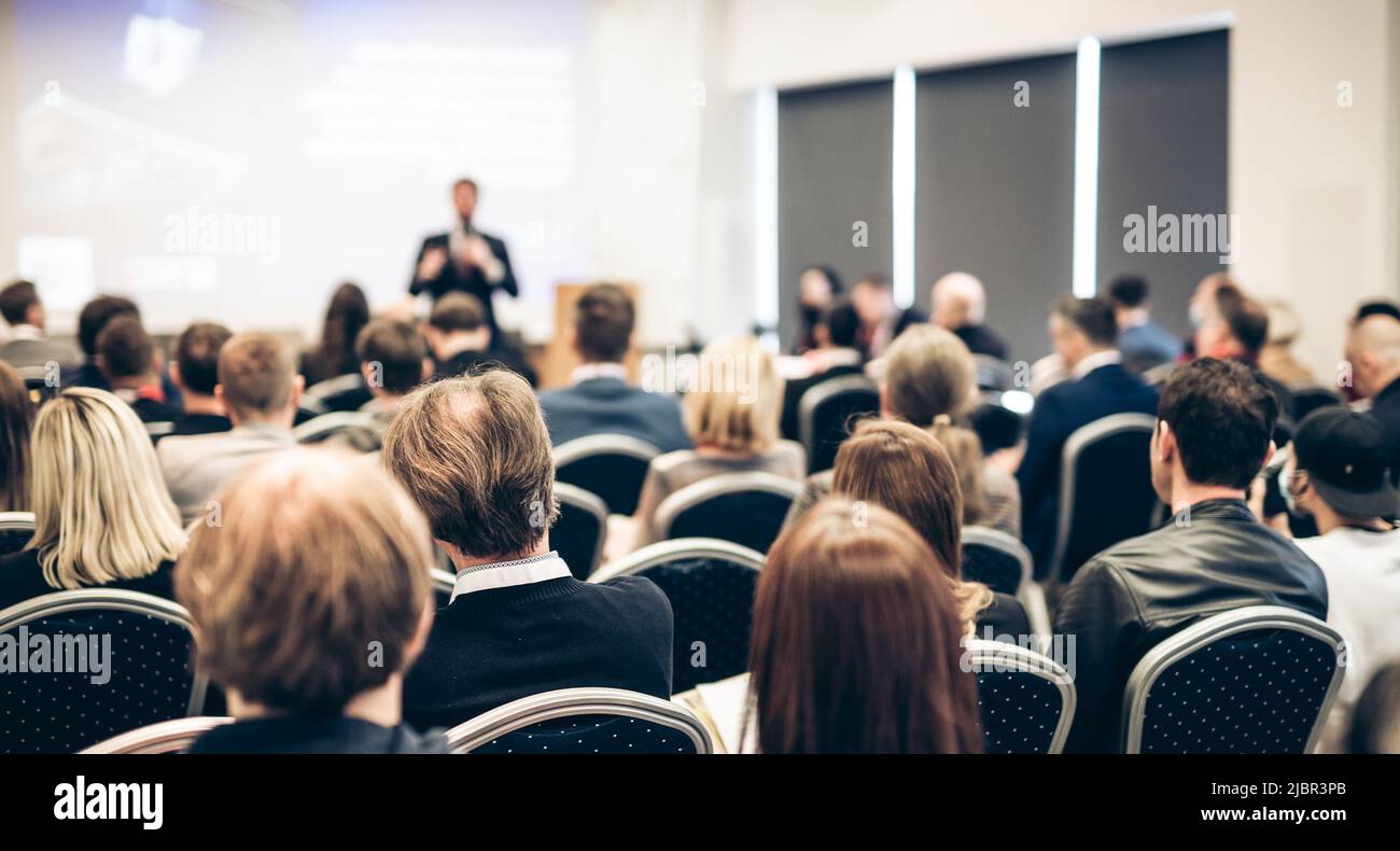 Referent, der bei einer Geschäftsveranstaltung im Konferenzsaal spricht. Rückansicht von nicht erkennbaren Personen im Konferenzsaal. Business und Stockfoto