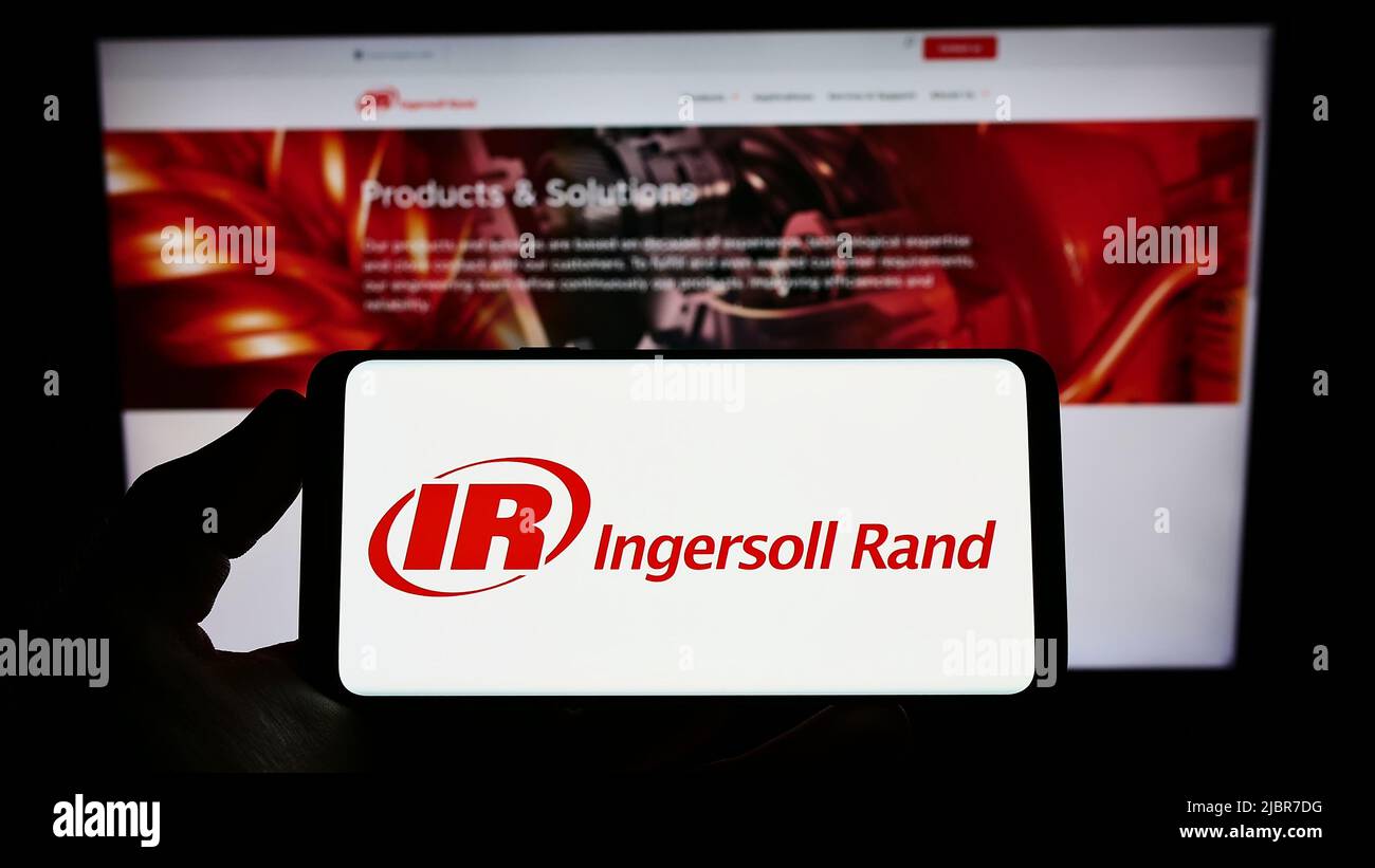 Person, die das Smartphone mit dem Logo des US-Maschinenunternehmens Ingersoll Rand Inc. (IR) auf dem Bildschirm vor der Website hält. Konzentrieren Sie sich auf die Telefonanzeige. Stockfoto