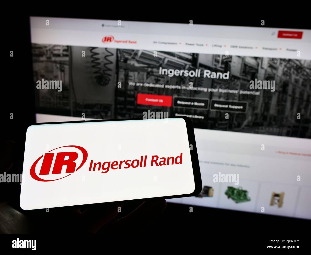 Person, die Mobiltelefon mit dem Logo des amerikanischen Maschinenbauunternehmens Ingersoll Rand Inc. (IR) auf dem Bildschirm vor der Webseite hält. Konzentrieren Sie sich auf die Telefonanzeige. Stockfoto