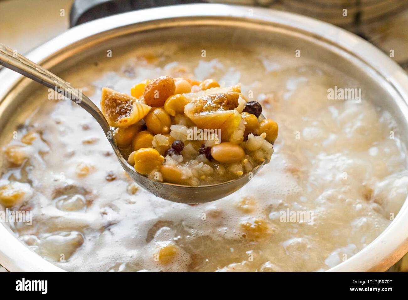 Kochen traditionelle Dessert Asure, Ashura oder Noah Pudding mit Edelstahl-Kochgeschirr auf dem Herd.Halten Sie eine Pfanne mit Zutaten in Dampf auf dem Topf. Stockfoto