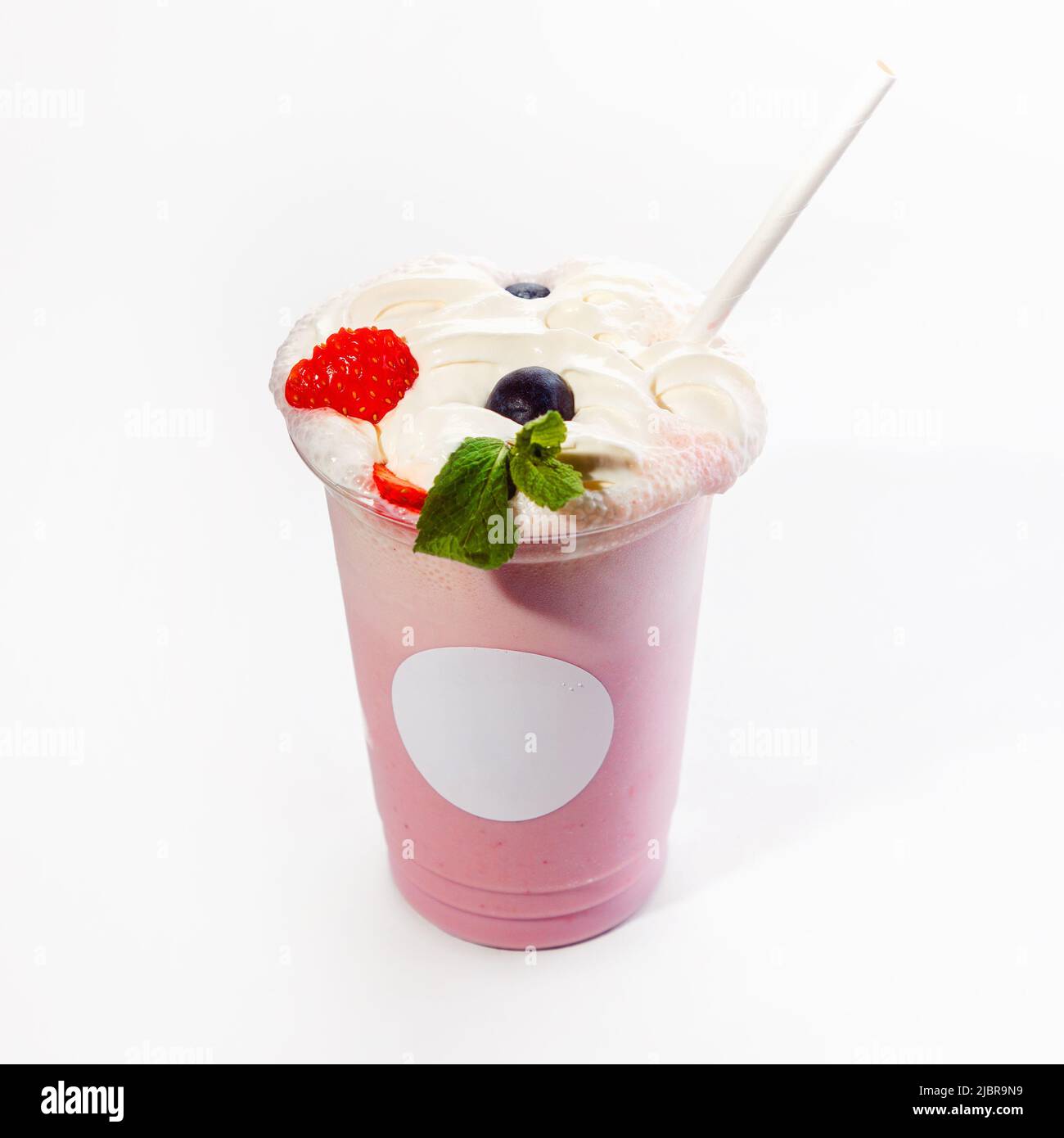 Kühler, köstlicher Milchshake mit Beerengeschmack und Schlagsahne, verziert mit Waldbeeren. Nahaufnahme auf weißem Hintergrund. Modell. Stockfoto
