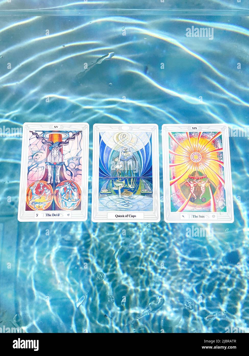 Thoth Astrology Tarot Card Deck im blauen Sommerpool mit leichten Fackeln. Stockfoto