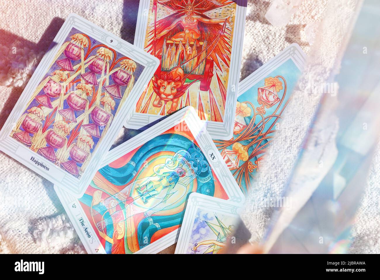 Thoth Astrology Tarot-Kartendeck, das auf einem unkonventionellen Picknickteppich mit Regenbogenlicht-Prisma verteilt ist. Stockfoto
