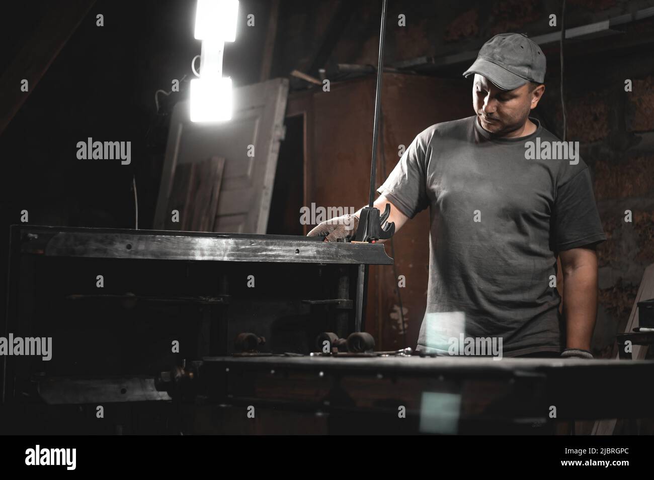 Ein Arbeiter bereitet eine Holzbearbeitungsmaschine für die Arbeit in seiner Hauswerkstatt vor. Herstellung von Metallprodukten mit eigenen Händen Stockfoto