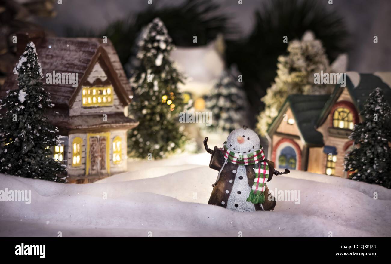 Ein nächtliches, von Schnee bedecktes Dorf mit einem einladenden Schneemann vor dem Hotel Stockfoto