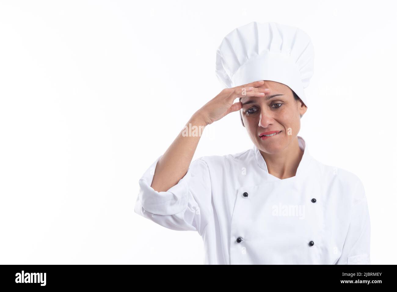 Junge Latina-Köchin, die gestresst und besorgt mit der Hand auf dem Kopf und dem Beißen ihrer Lippen auf weißem Hintergrund mit Kopierraum aussieht. Stockfoto