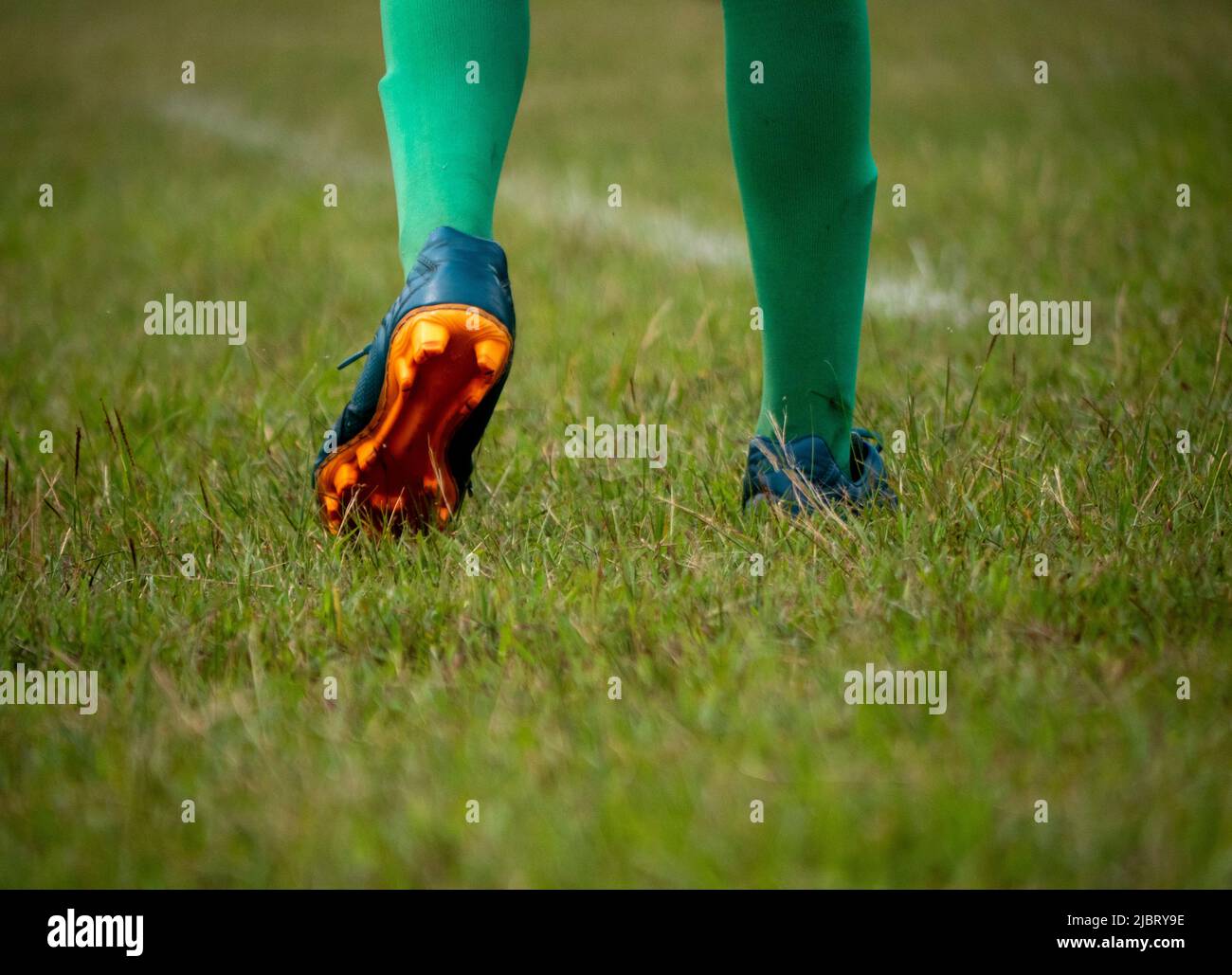 Fußballspieler in Fußballschuhen beim Gehen auf Gras mit selektivem Fokus. Stockfoto