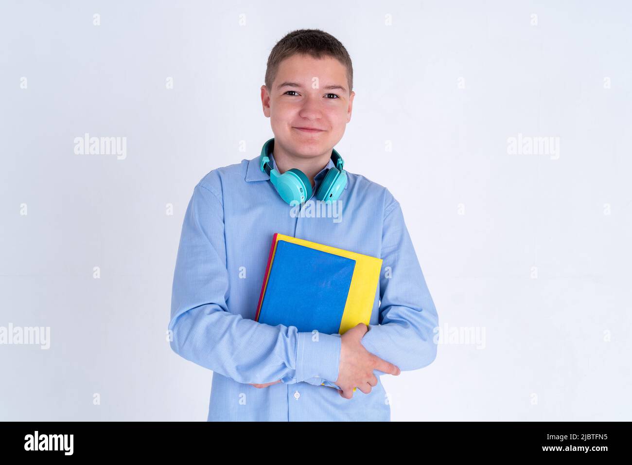 Porträt eines kaukasischen Teenagers in einem blauen Hemd mit Mockup-Büchern. Das Konzept von Bildung und Kursen. Stockfoto