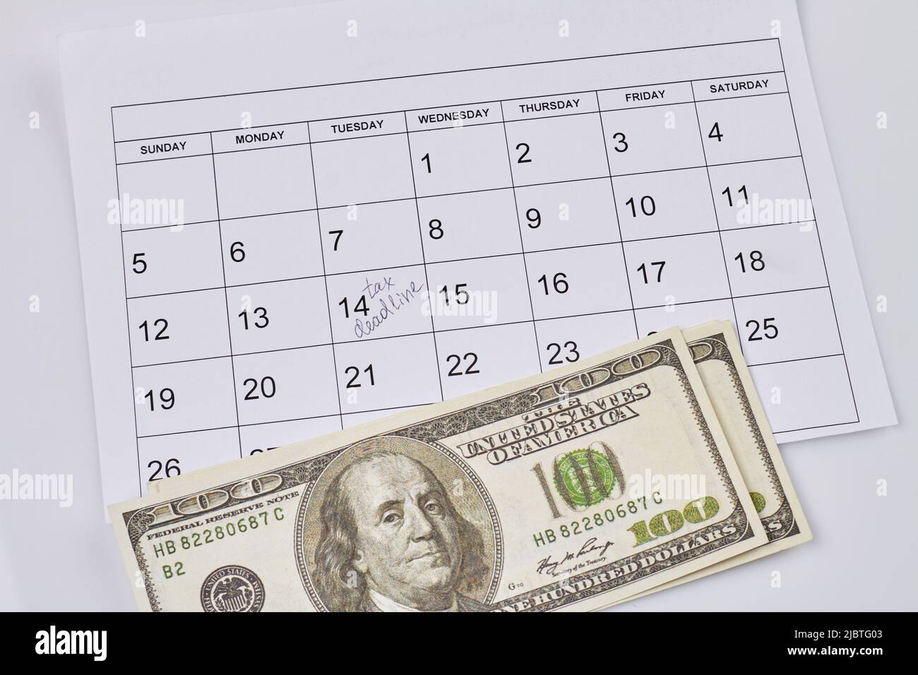 Steuerfristkonzept. Dollar-Banknoten und Kalender mit markierter Datumsangabe. Draufsicht flach liegend. Stockfoto