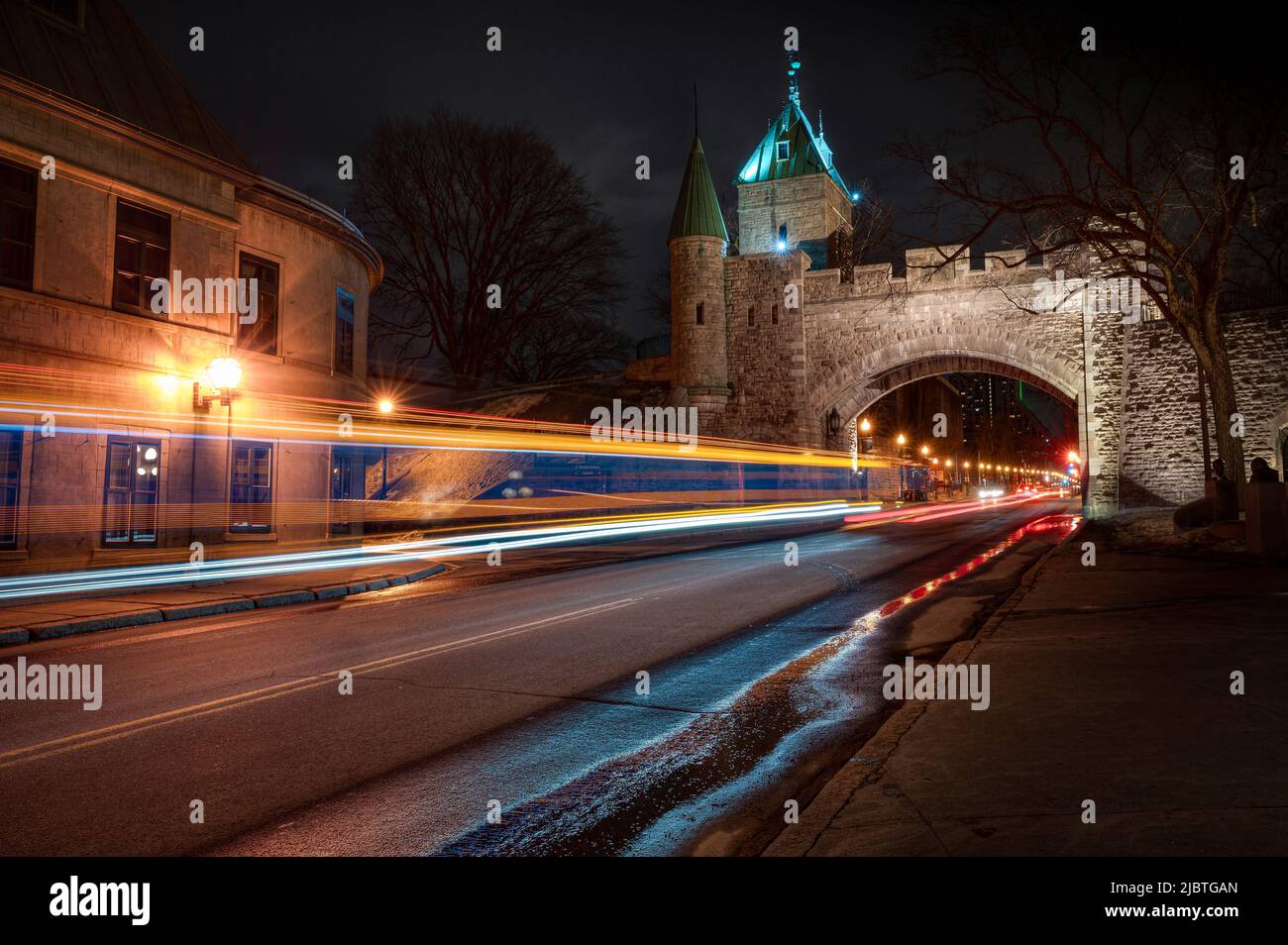 St-Louis Gate, Bogen in Befestigungsanlagen von Quebec City bei Nacht, während Autos und Bus vorbeifahren, QC, Kanada Stockfoto