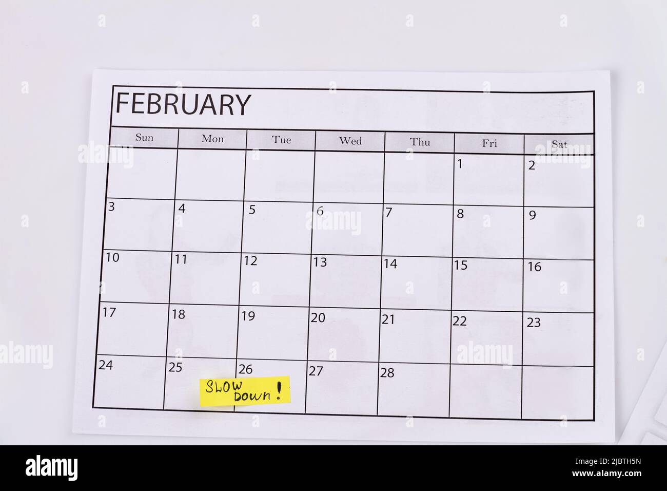 Februarkalender und Verlangsamung auf weißem Hintergrund. Faulheit Tageskonzept. Stockfoto