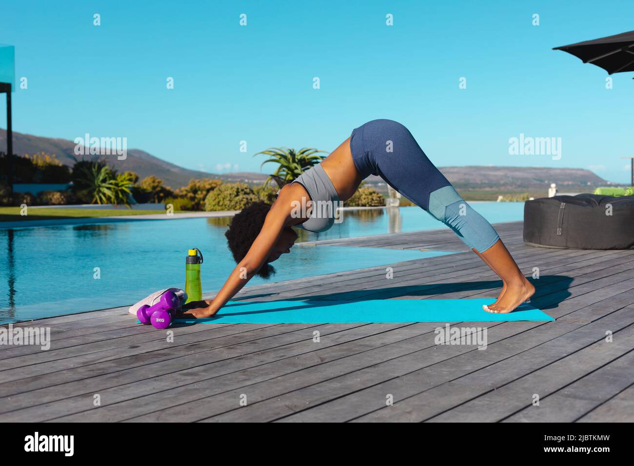 afroamerikanische junge Frau, die im Freien in der Nähe des Pools Yoga praktiziert Stockfoto