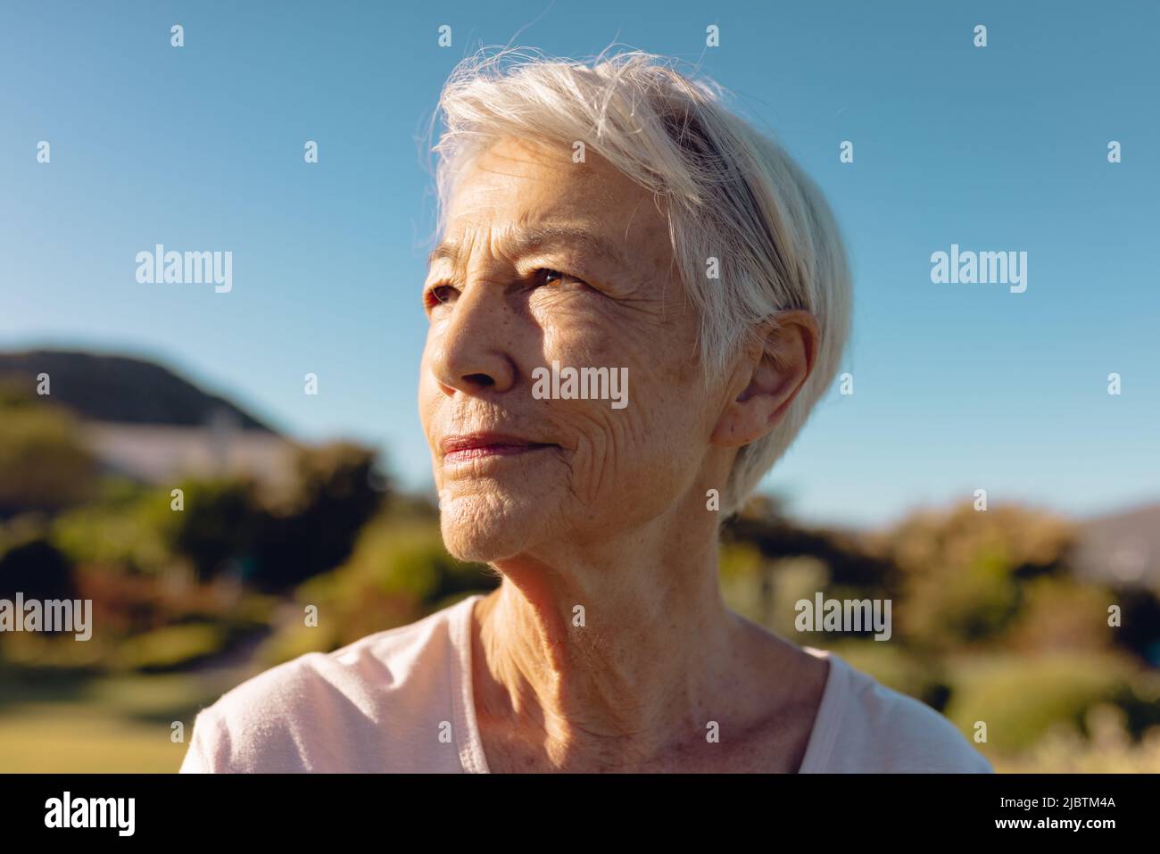 Nahaufnahme einer ernsthaften asiatischen älteren Frau, die vor dem klaren blauen Himmel im Hof nachdenkt, Raum kopieren Stockfoto