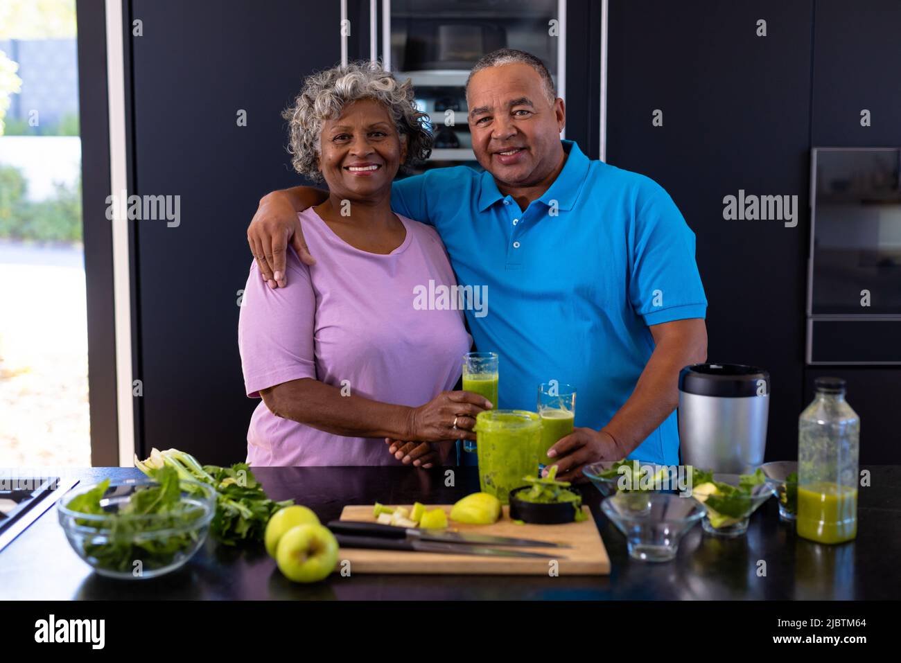 Porträt von lächelnden, multirassischen älteren Freunden mit Smoothie, Obst und Gemüse auf der Küchentheke Stockfoto