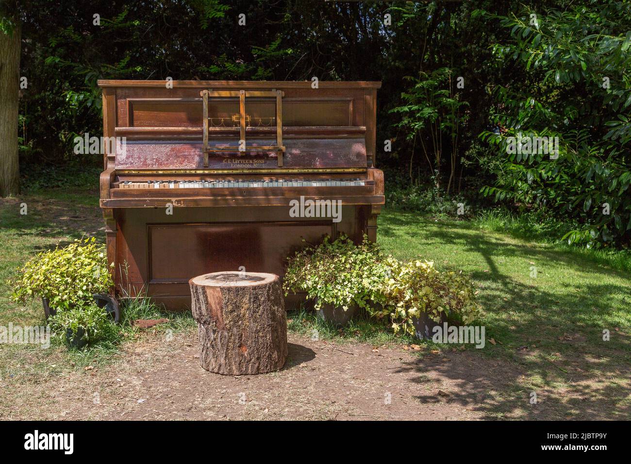 Ein baufälliges Klavier, das allein auf einem Feld steht. Unerwünschte, Einsamkeit, Verlassenheit oder Urlaub, Änderung des Szenenkonzepts. Stockfoto