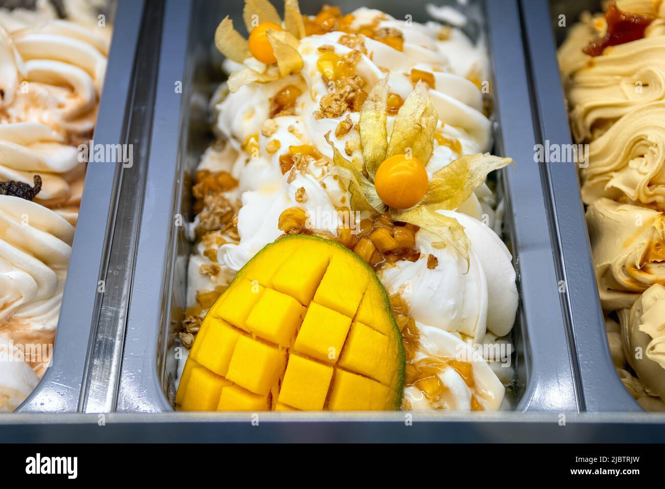 Mango-Eis mit Physalis. Verschiedene Eiscreme auf Tabletts in der Eisdiele, Ansicht von oben. Stockfoto