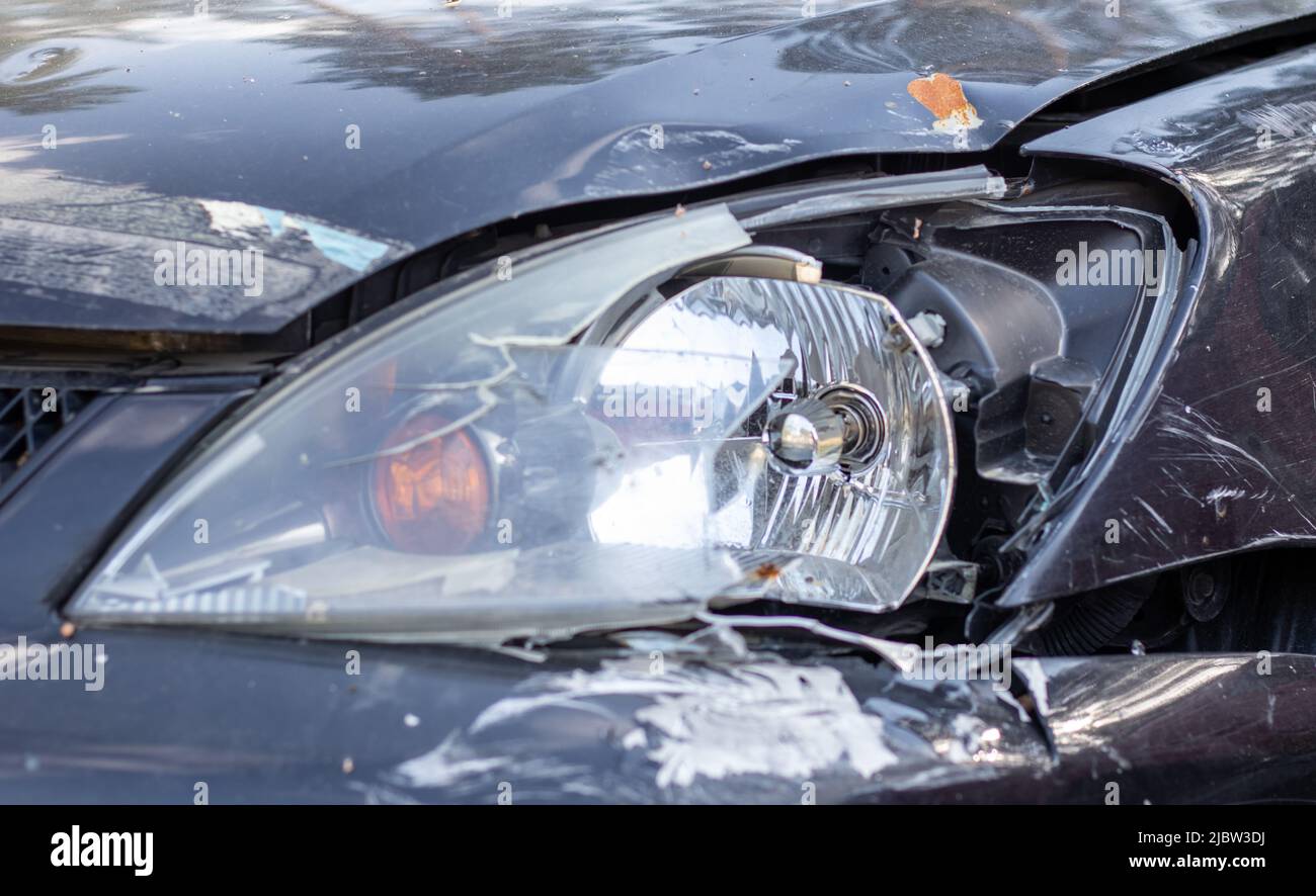 Defekte Scheinwerfer infolge einer Kollision. Kaputtes schwarzes Auto nach einem Unfall. Konzept eines Autounfalls. Notscheinwerfer, Motorhaube und Stoßfänger beschädigt. Stockfoto