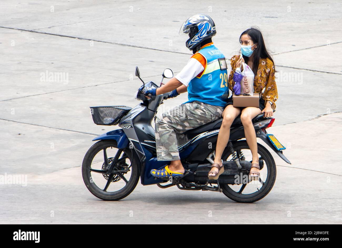 SAMUT PRAKAN, THAILAND, APR 04 2022, Ein Taxifahrer auf einem Motorrad fährt mit einer Frau. Das Moto-Taxi trägt einen Passagier Stockfoto