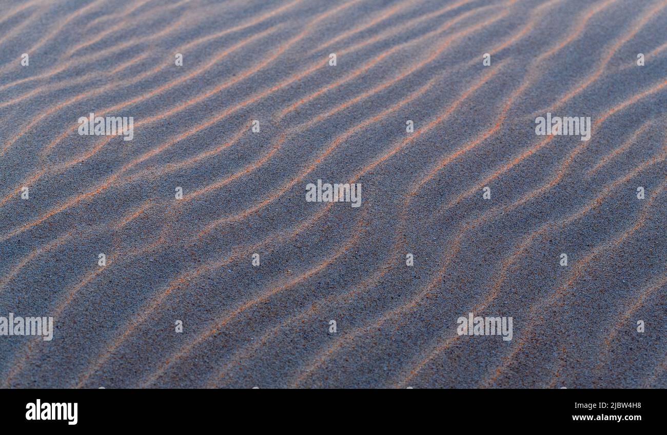 Sand kräuselt Textur mit Wellen bei Sonnenuntergang als Hintergrund oder Tapete. Stockfoto
