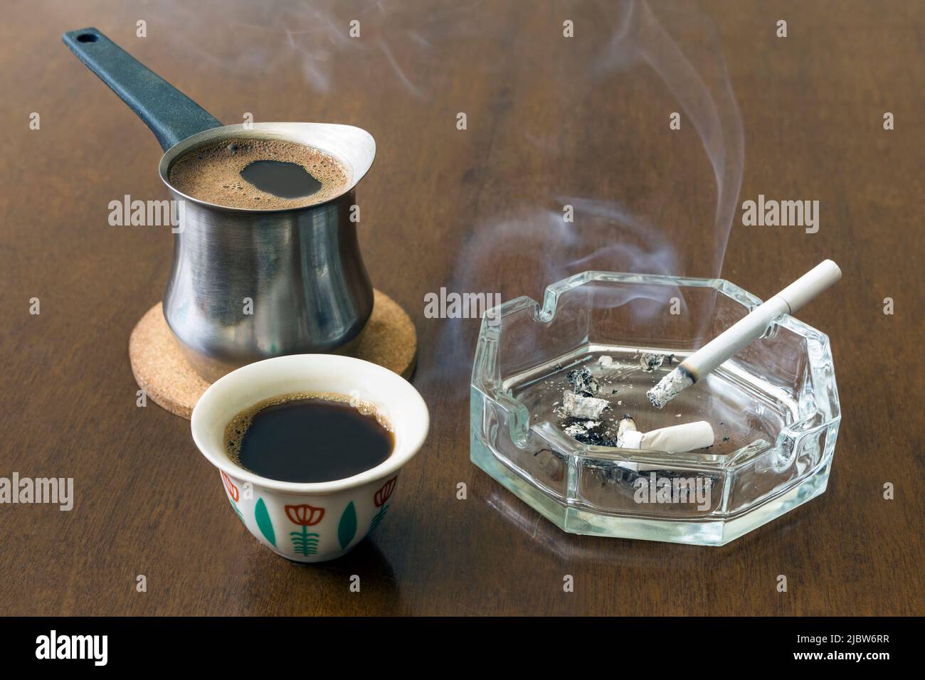 Traditionelle libanesische Kaffeebecher mit Aschenbecher und Zigarette auf einem Holztisch Stockfoto