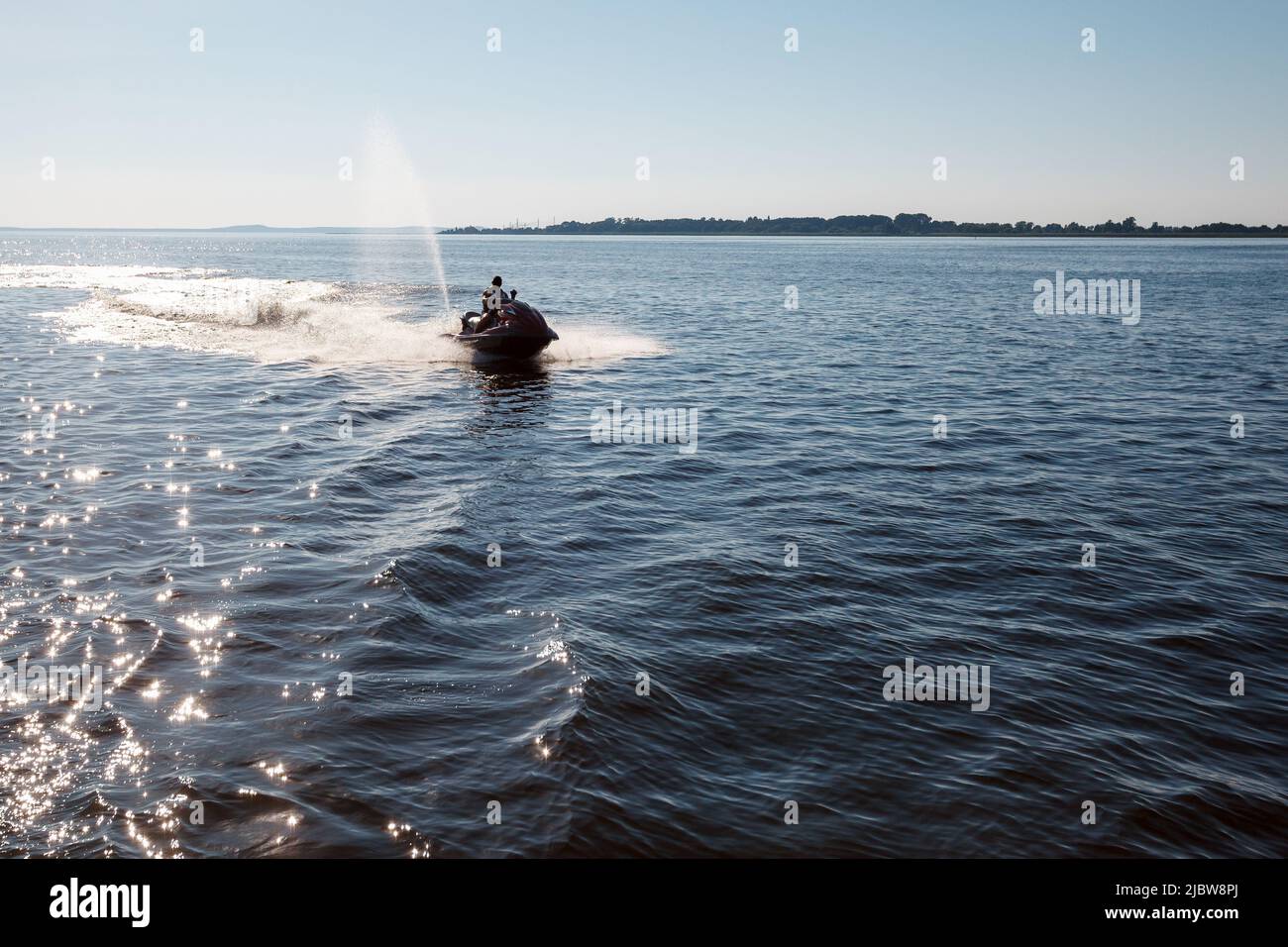 Mittags springt die Silhouette eines starken Mannes auf den Jetski über dem Wasser Stockfoto