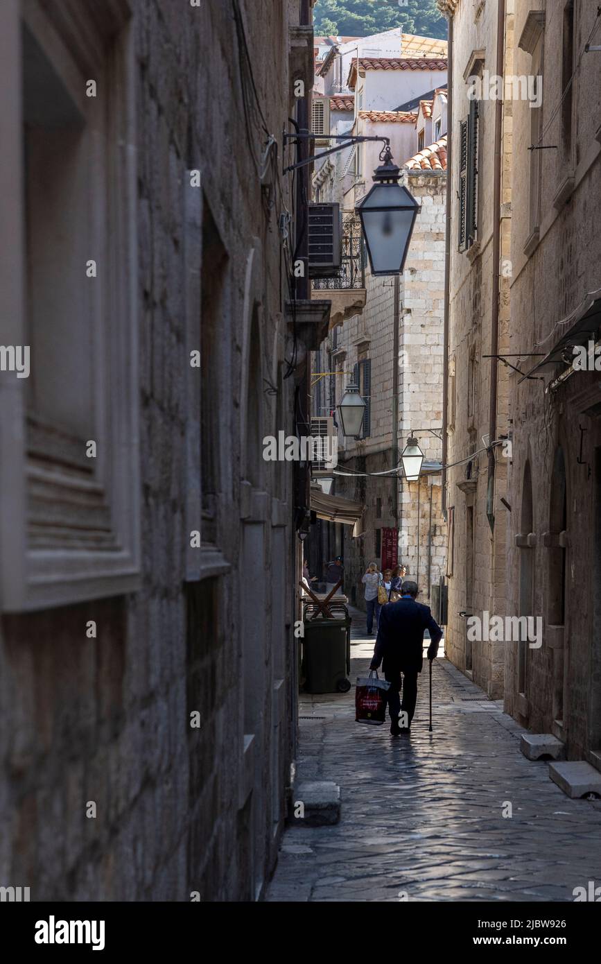 Älterer Mann mit Stock zu Fuß in der engen Straße in der Altstadt, Dubrovnik, Kroatien Stockfoto