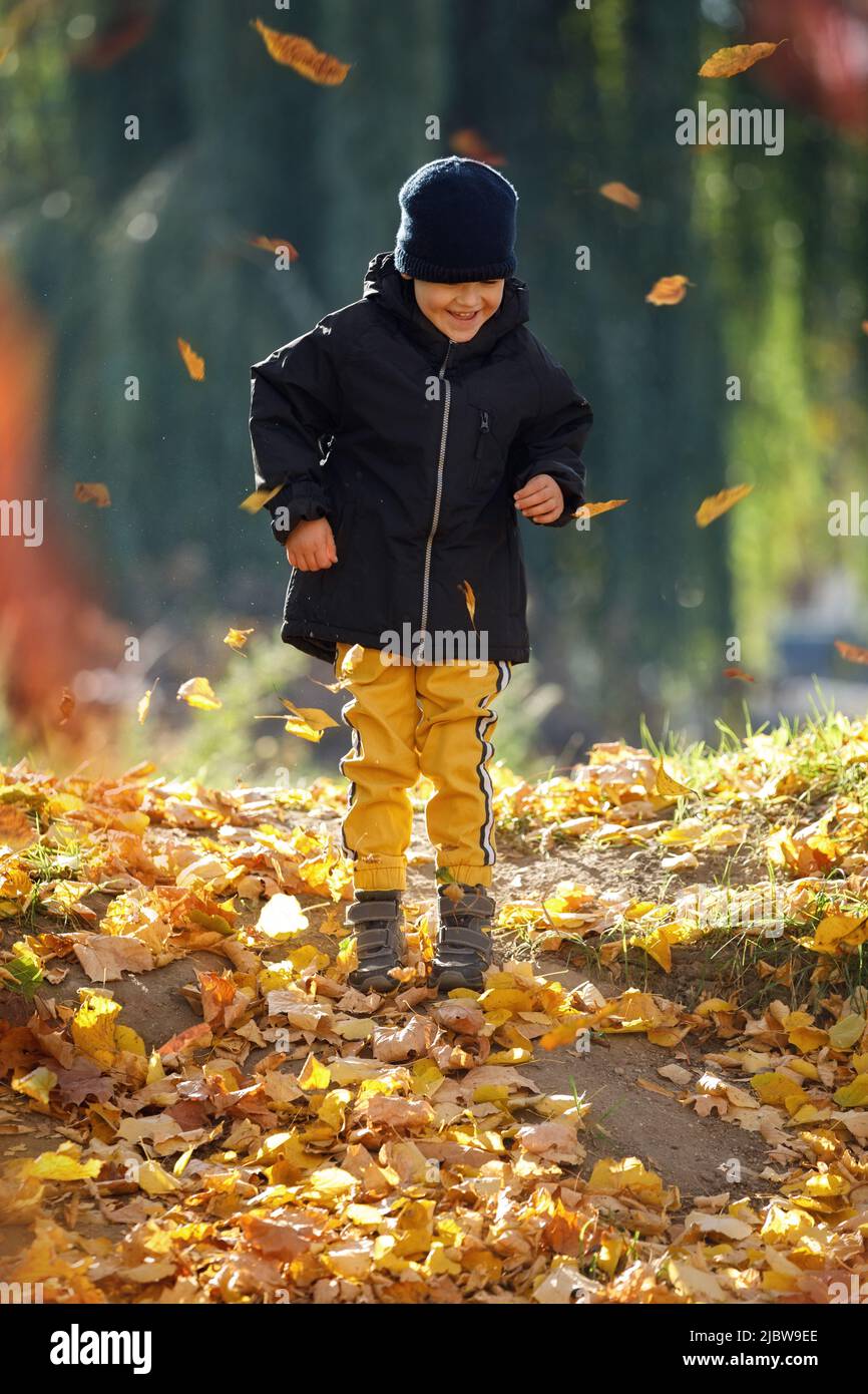 Glückliches Kind, das in gelben Herbstblättern spielt. Einfaches Glück. Süße Kindheitserinnerungen. Stockfoto
