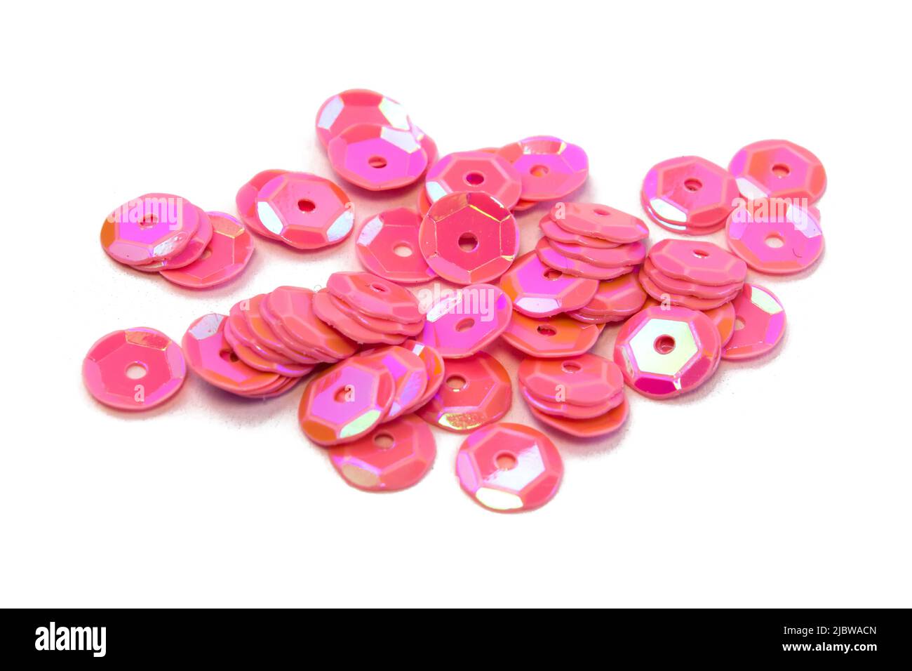 Helle schöne rosa funkelt Pailletten auf weißem strukturierten Hintergrund verstreut, Nahaufnahme Draufsicht Makrofoto Stockfoto