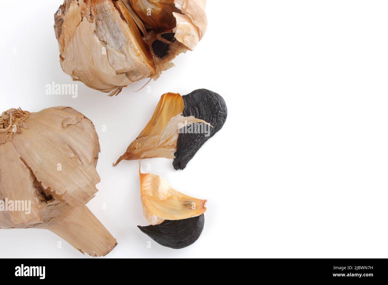 Schwarze Knoblauchzwiebeln mit Nelken isoliert auf weißem Hintergrund. Speicherplatz kopieren. Draufsicht. Stockfoto