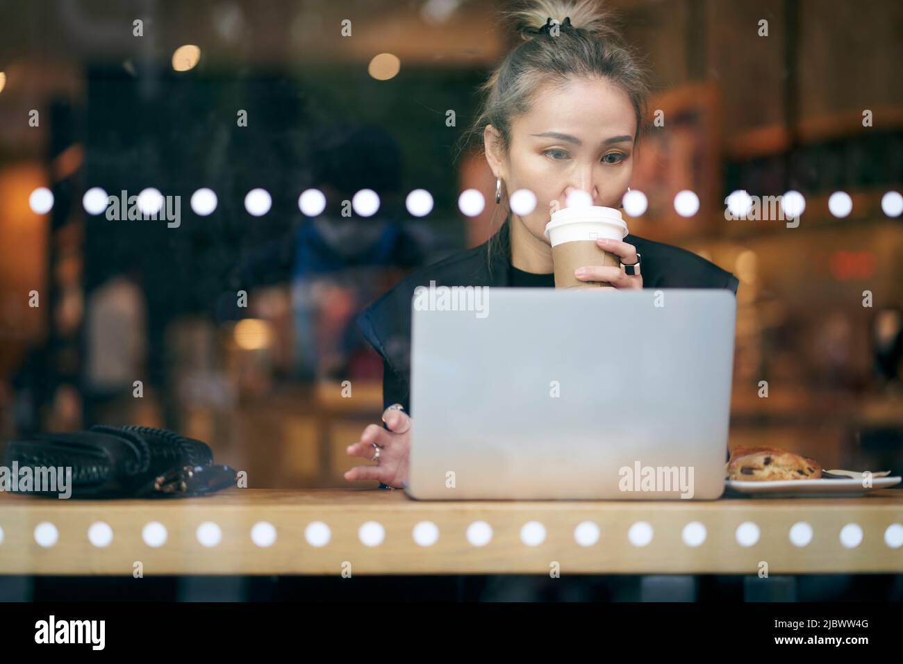 Mittelgroße asiatische Geschäftsfrau, die im Café mit einem Laptop arbeitet Stockfoto